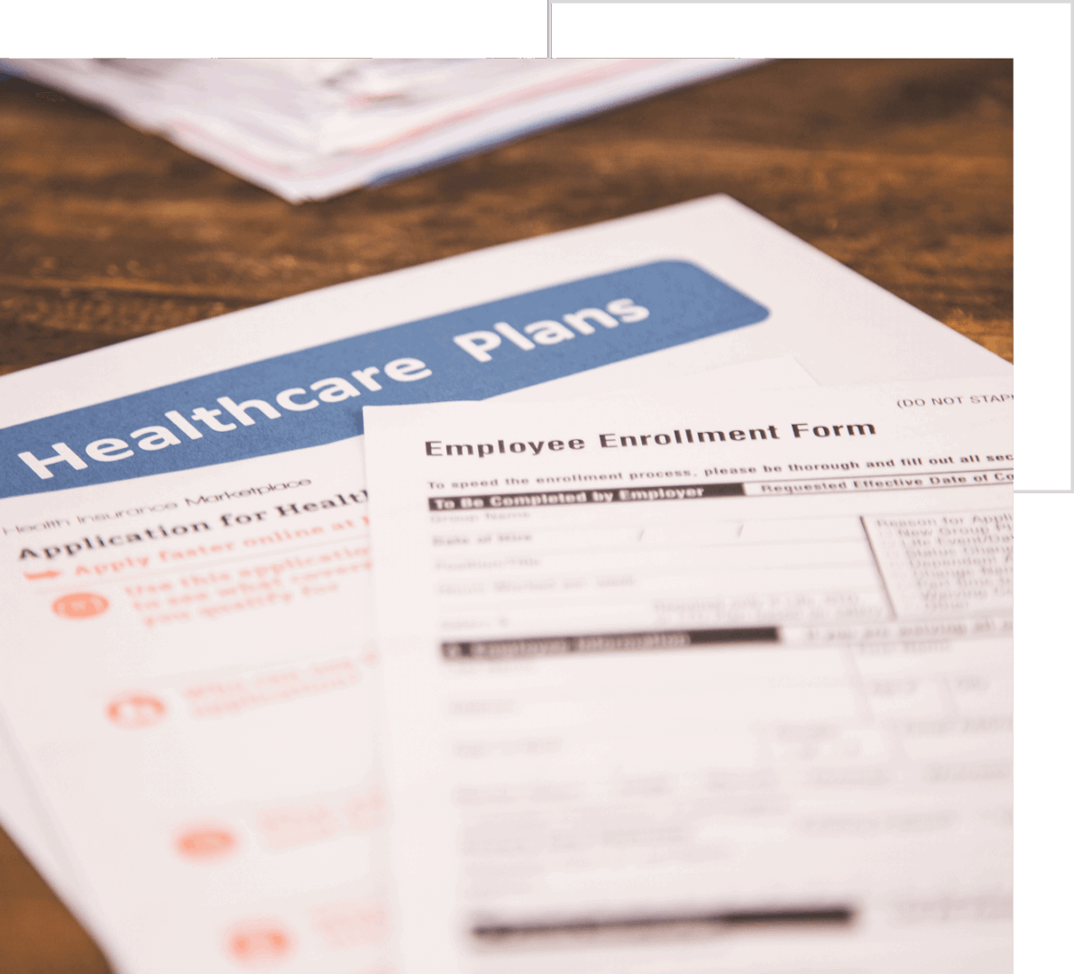 Close-up of healthcare plans forms on a wooden table, with some text and options visible but partially blurred.