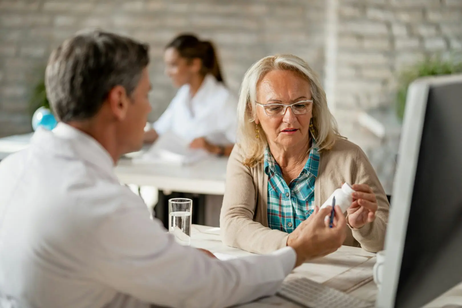 A woman consulting a doctor in a medical office, discussing health information with focus and concern.